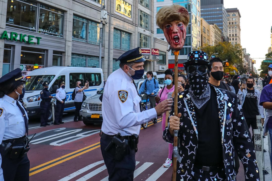 A police officer in Union Square tells a man holding a Trump head on a stick something